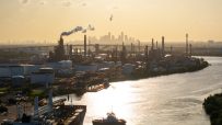 Sprawling oil refinery with complex network of pipes and towers under a clear sky, highlighting industrial energy production.