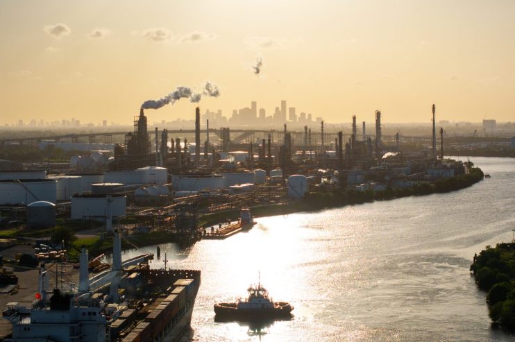Sprawling oil refinery with complex network of pipes and towers under a clear sky, highlighting industrial energy production.