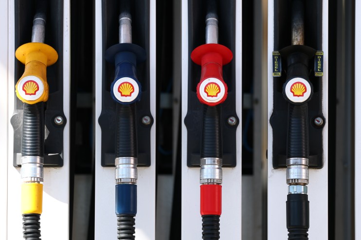 Petrol station with fuel pumps, signage displaying fuel prices, vehicles refueling, and customers engaging with attendants