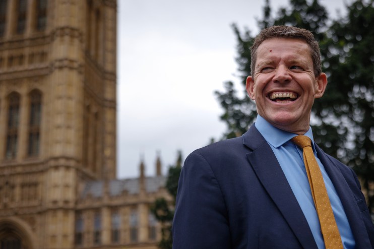 Plaid Cymru leader Rhun ap Iorwerth addressing the crowd at a public event, wearing a suit and speaking passionately