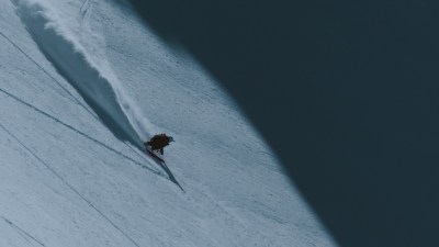 Skiing enthusiast gliding down a snowy slope with clear blue skies, showcasing winter sports excitement and adventure
