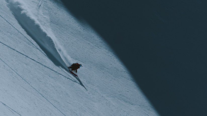 Skiing enthusiast gliding down a snowy slope with clear blue skies, showcasing winter sports excitement and adventure