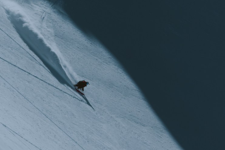Skiing enthusiast gliding down a snowy slope with clear blue skies, showcasing winter sports excitement and adventure