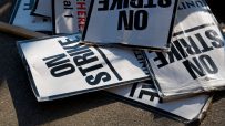 Workers holding signs and banners in a strike action, demanding better working conditions and wages in a public demonstrat...