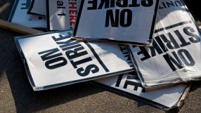 Workers holding signs and banners in a strike action, demanding better working conditions and wages in a public demonstrat...