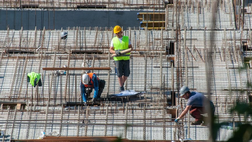 Busy construction site with cranes and workers building a new structure, showcasing urban development progress