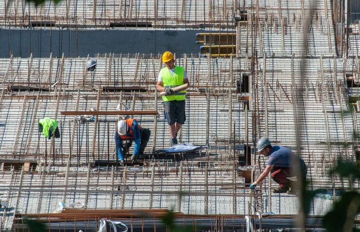 Busy construction site with cranes and workers building a new structure, showcasing urban development progress
