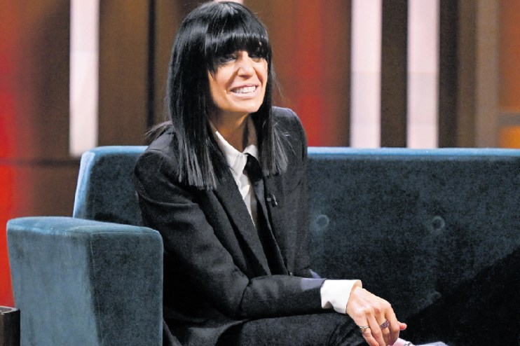 Claudia Winkleman at a press event, wearing a stylish outfit, speaking with journalists, showcasing her iconic fringe hair...