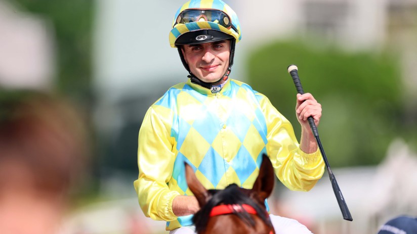 Jockey Andrea Atzeni riding a horse during a competitive race at a renowned international racing event.