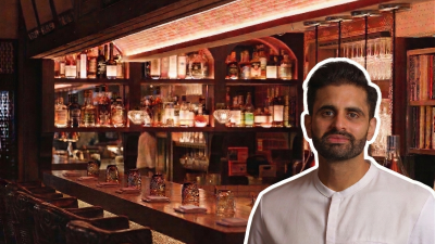 Chet Sharma speaking at a business conference podium with a projector screen displaying financial graphs in the background