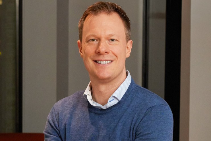 ClearBank CEO Mark Fairless in a business suit, confidently addressing an audience at a corporate event.