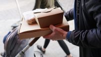 Restaurant staff handing a neatly packed doggy bag to a customer, highlighting sustainable takeout practices and customer ...
