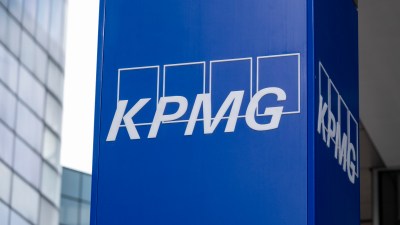 KPMG logo prominently displayed on a modern office building fa&ccedil;ade against a clear blue sky, symbolizing corporate presence