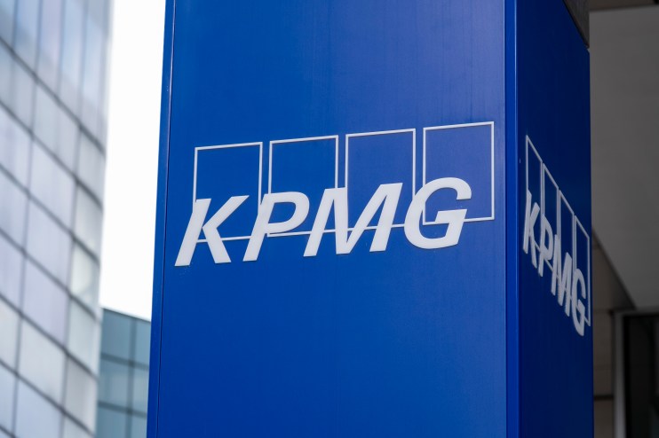 KPMG logo prominently displayed on a modern office building façade against a clear blue sky, symbolizing corporate presence