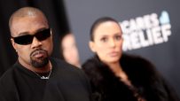 Kanye West attending a public event, wearing stylish attire, capturing media attention amidst ongoing news discussions