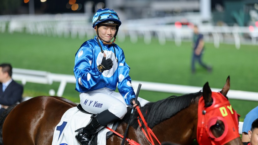 Nichola Yuen smiling during an interview, wearing a blue blazer with a cityscape background in a business news setting