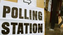 Polling station exterior with voters lining up for local election in a community setting with clear signage and ballot box...