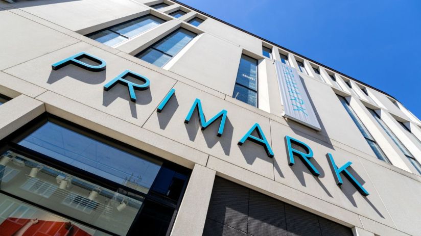 Primark storefront with shoppers entering and exiting, showcasing the latest fashion trends and bustling retail activity.