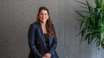 Sophie Maryan presenting at a conference podium, engaged audience, business attire, professional setting, focused expression