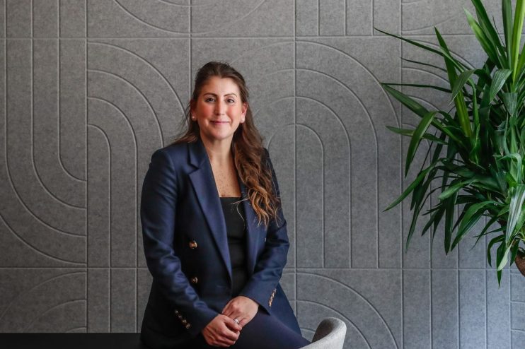 Sophie Maryan presenting at a conference podium, engaged audience, business attire, professional setting, focused expression