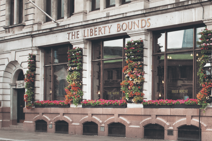 The Liberty Bounds Wetherspoons pub exterior with patrons and bustling street scene in central London