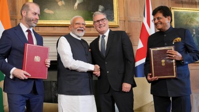 UK and India representatives signing trade agreement at formal meeting with flags and documents visible on the table