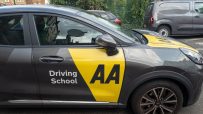 AA Driving School instructor teaching a student driver in a car, focusing on hands-on driving techniques and safety tips.