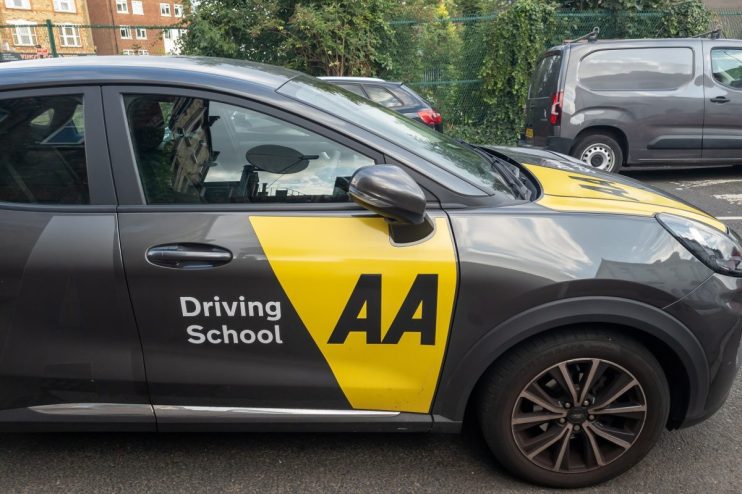 AA Driving School instructor teaching a student driver in a car, focusing on hands-on driving techniques and safety tips.