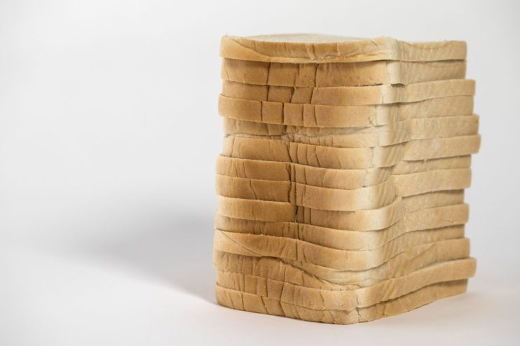 Freshly baked artisan bread with golden crust displayed on a wooden surface, highlighting texture and quality for culinary...