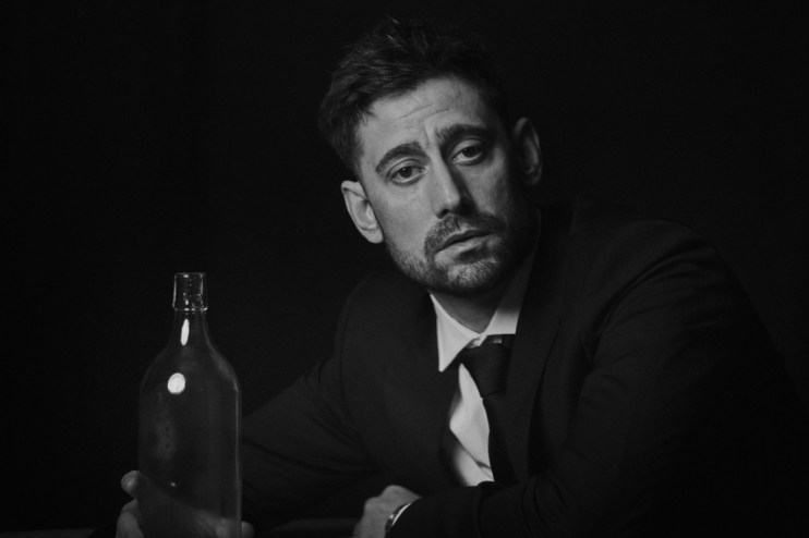 Michael Socha appearing at a public event, dressed in a suit, engaging with an audience, conveying professionalism and cha...