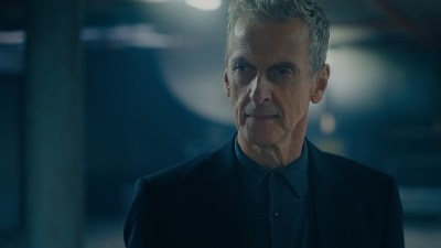 Peter Capaldi smiling in a suit at a public event, showcasing his charismatic presence and style.