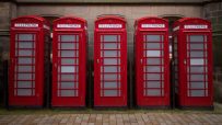 Classic red phone boxes lining a street, symbolizing British heritage and communication history.