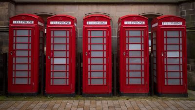 Classic red phone boxes lining a street, symbolizing British heritage and communication history.