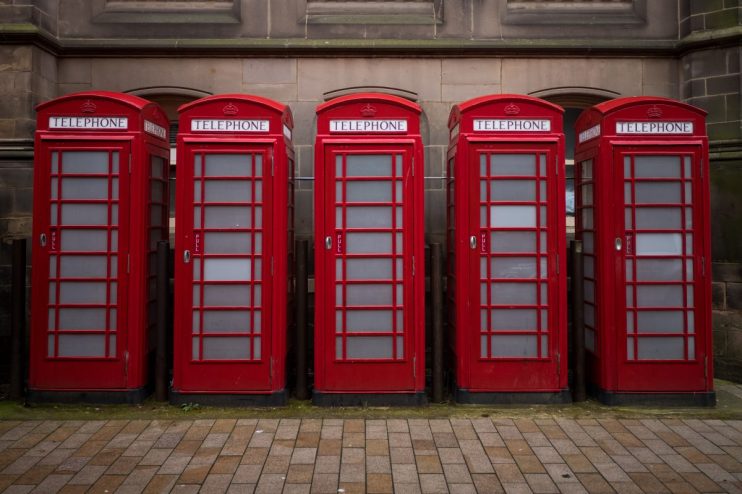 Classic red phone boxes lining a street, symbolizing British heritage and communication history.