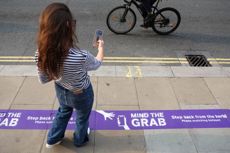 Person holds smartphone tightly in crowded urban area, highlighting phone theft concerns in bustling city environments.