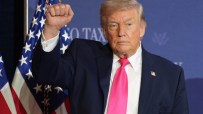 Donald Trump raising his fist in a confident gesture during a public appearance, symbolizing determination and leadership