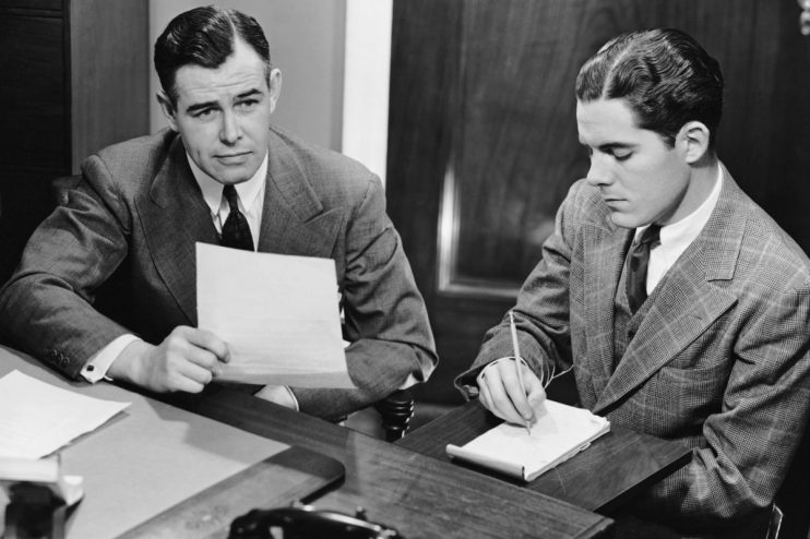 Office workers collaborating at desks, engaging in teamwork and discussions, enhancing productivity in a modern business e...