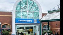 Aylesham town center bustling with shoppers and vibrant storefronts on a sunny day, highlighting community engagement