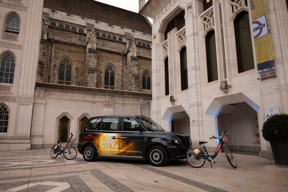 Taxi arriving at City AM Awards venue with illuminated city skyline in the background, highlighting urban business excellence