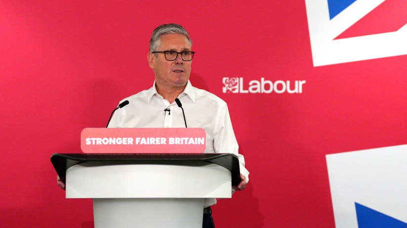 Keir Starmer delivering a speech at a podium, addressing audience with focused expression, highlighting key political points