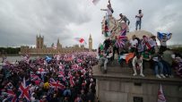 Crowd gathers in London for Unite the Kingdom rally, holding banners and flags, advocating for national unity and solidarity.