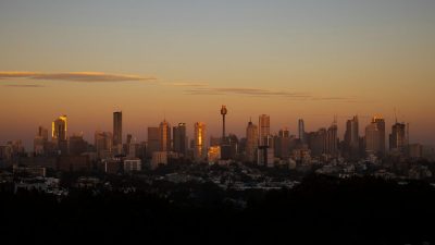 Sydney skyline view with iconic Opera House and Harbour Bridge under clear blue skies, highlighting Australias vibrant cit...