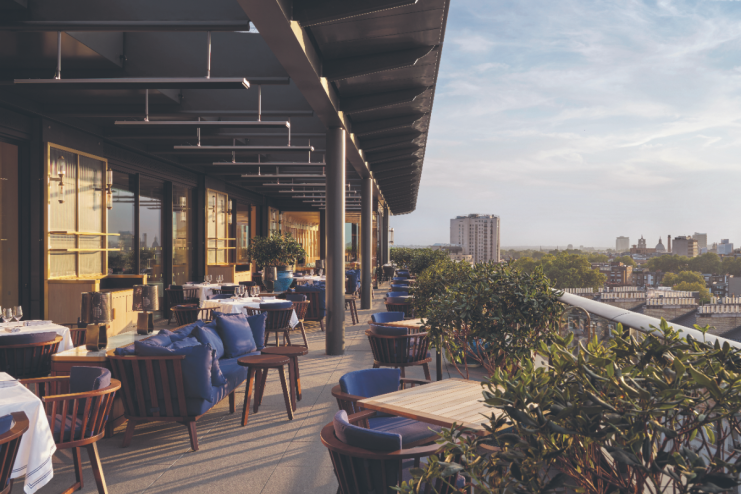 London skyline view from a rooftop bar in Kensington and Chelsea, featuring stylish seating and vibrant evening atmosphere