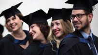 Young UK graduates from Gen Z celebrating in caps and gowns, representing the future workforce and educational achievements.