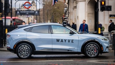 Wayve autonomous vehicle navigating a busy London street with iconic cityscape in the background