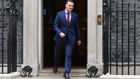 Wes Streeting addressing media at a public event, wearing a suit and tie, with a focused expression and microphones visible