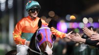 Zac Purton in a dynamic pose during a horse racing event, showcasing skill and concentration on the racetrack
