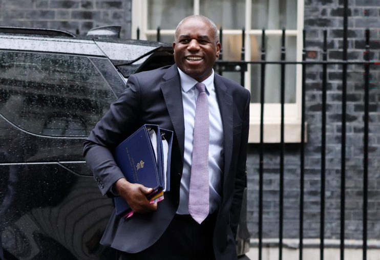 David Lammy speaking at a podium during a press conference, wearing a suit and addressing the audience with a serious expr...