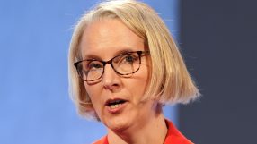 Emma Reynolds speaking at a business conference podium, engaging audience with insights on industry trends and strategies.