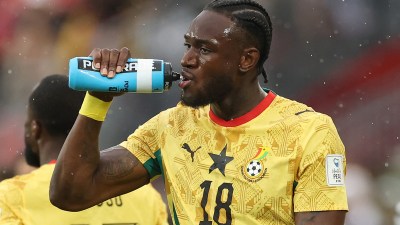Football players taking a hydration break during a World Cup match, highlighting the divisive pause amid rising temperatures.